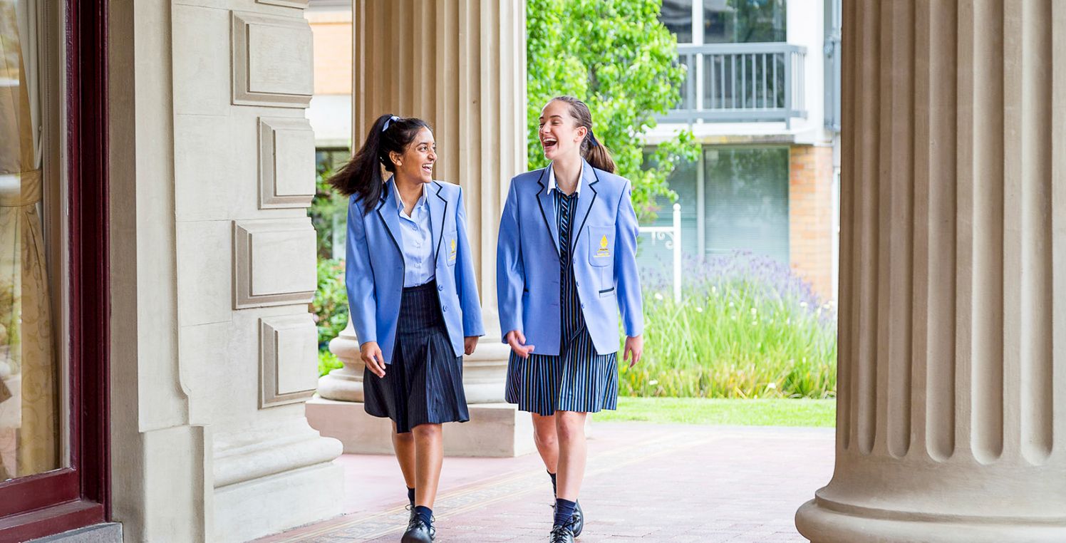 Two students laugh walking through school grounds