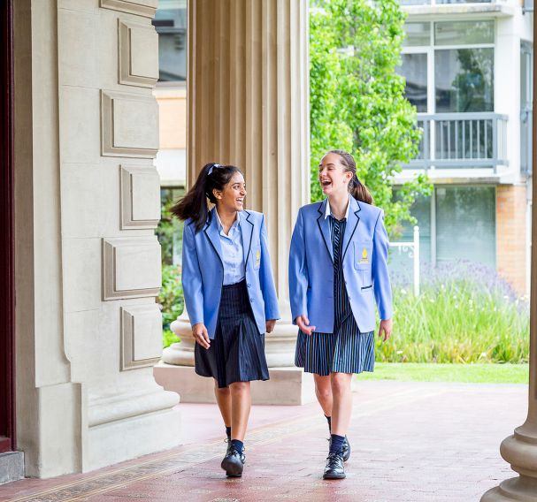 Two students laugh walking through school grounds