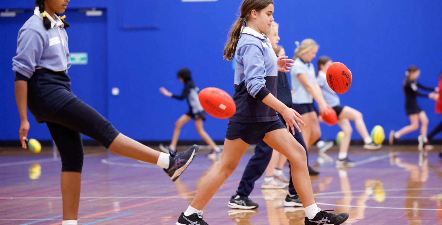 girls kicking football inside